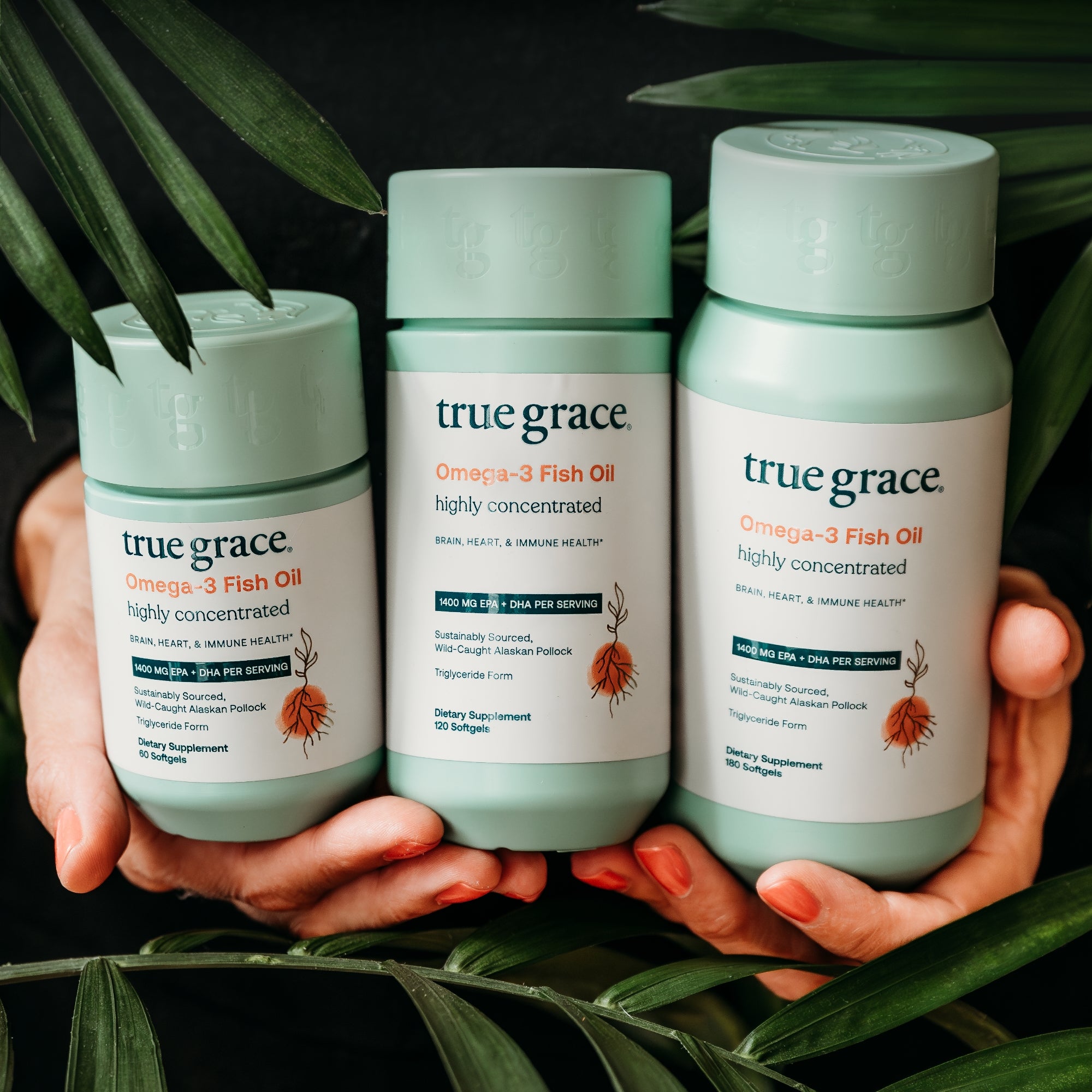 Three bottles of True Grace Omega-3 Fish Oil held between hands with a leafy background.