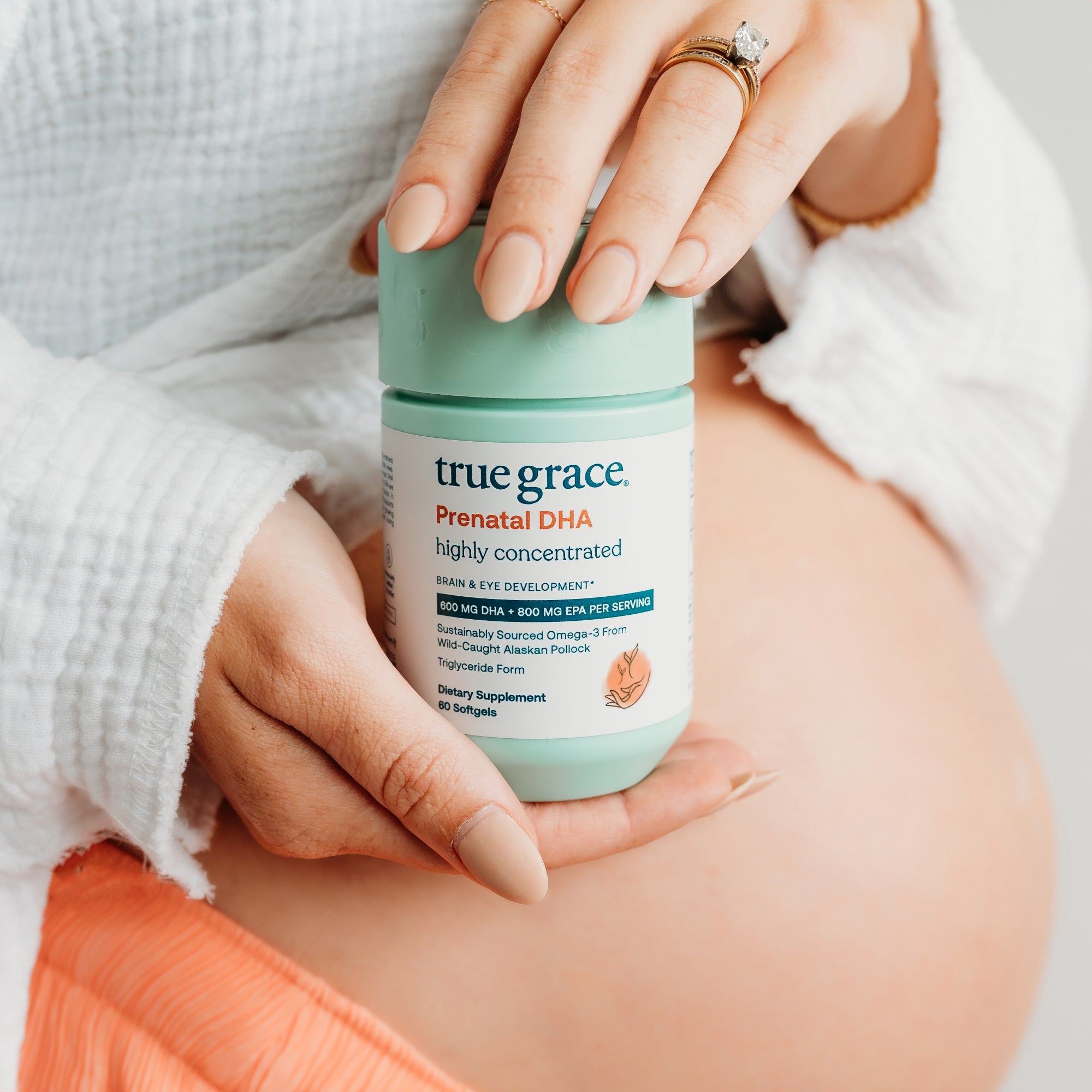 Person holding a container of True Grace Prenatal DHA highly concentrated vitamin supplement
