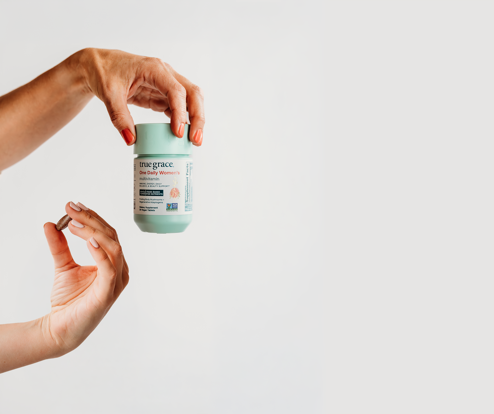 True Grace supplement bottle and hand holding pill on light background