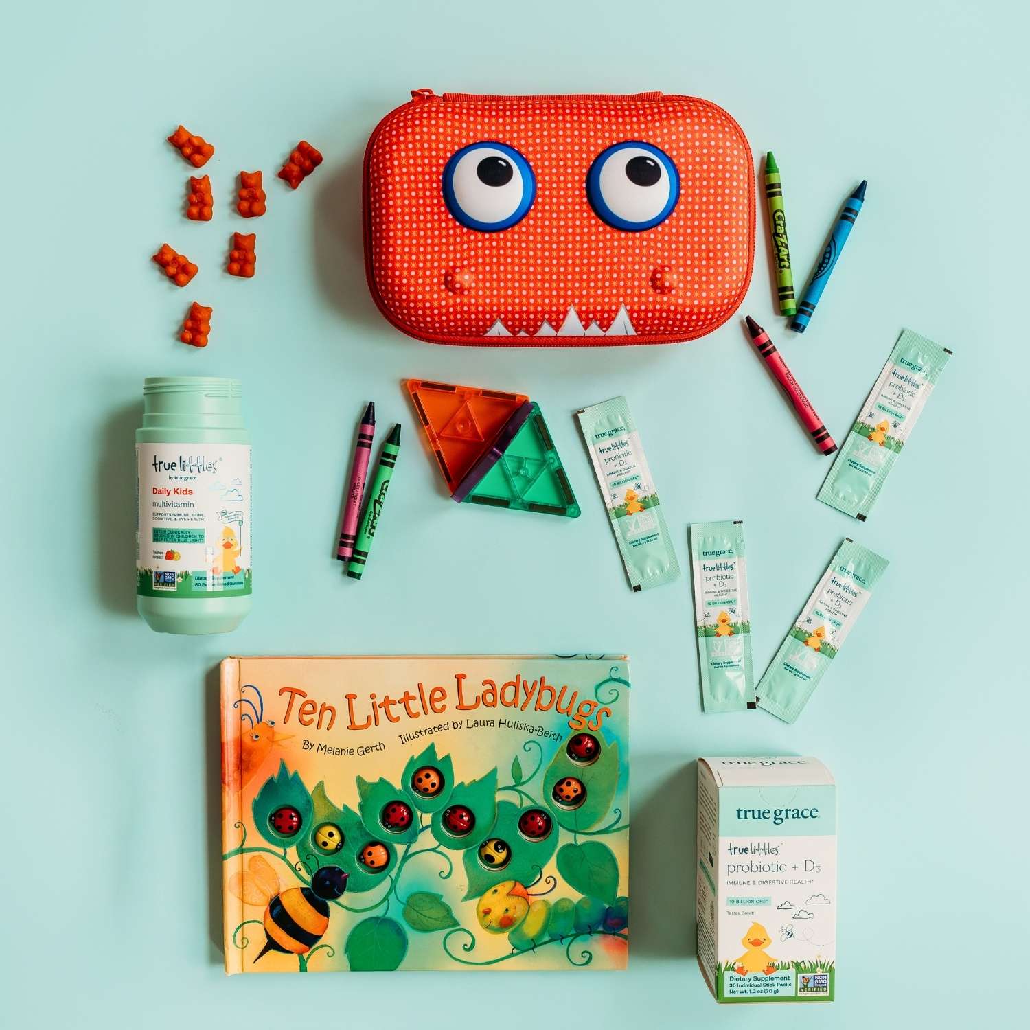 Collection of children's products including a red monster-shaped container, toys, and health products on a light blue background.
