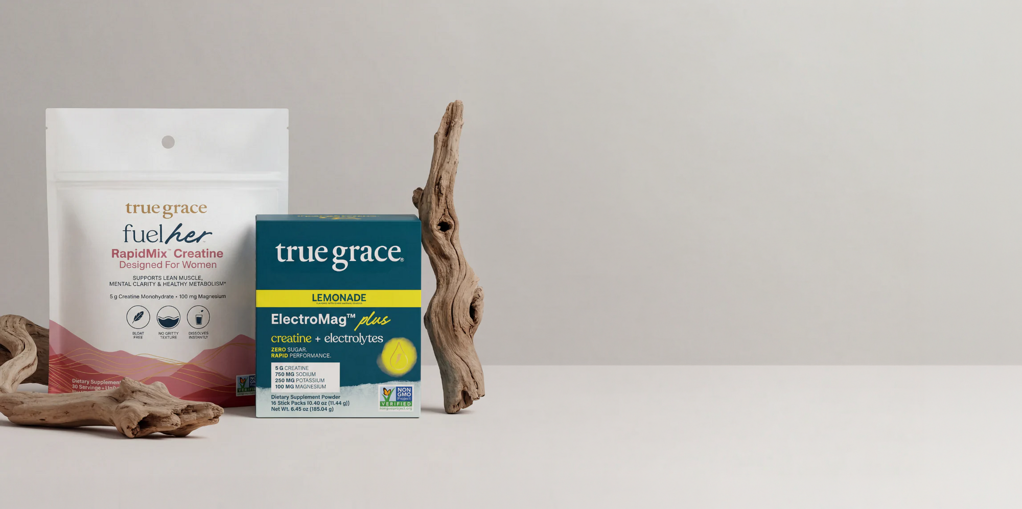 True Grace products including a package of FuelHer RapidMix Creatine and a box of True Grace ElectroMag Plus Lemonade on a neutral background
