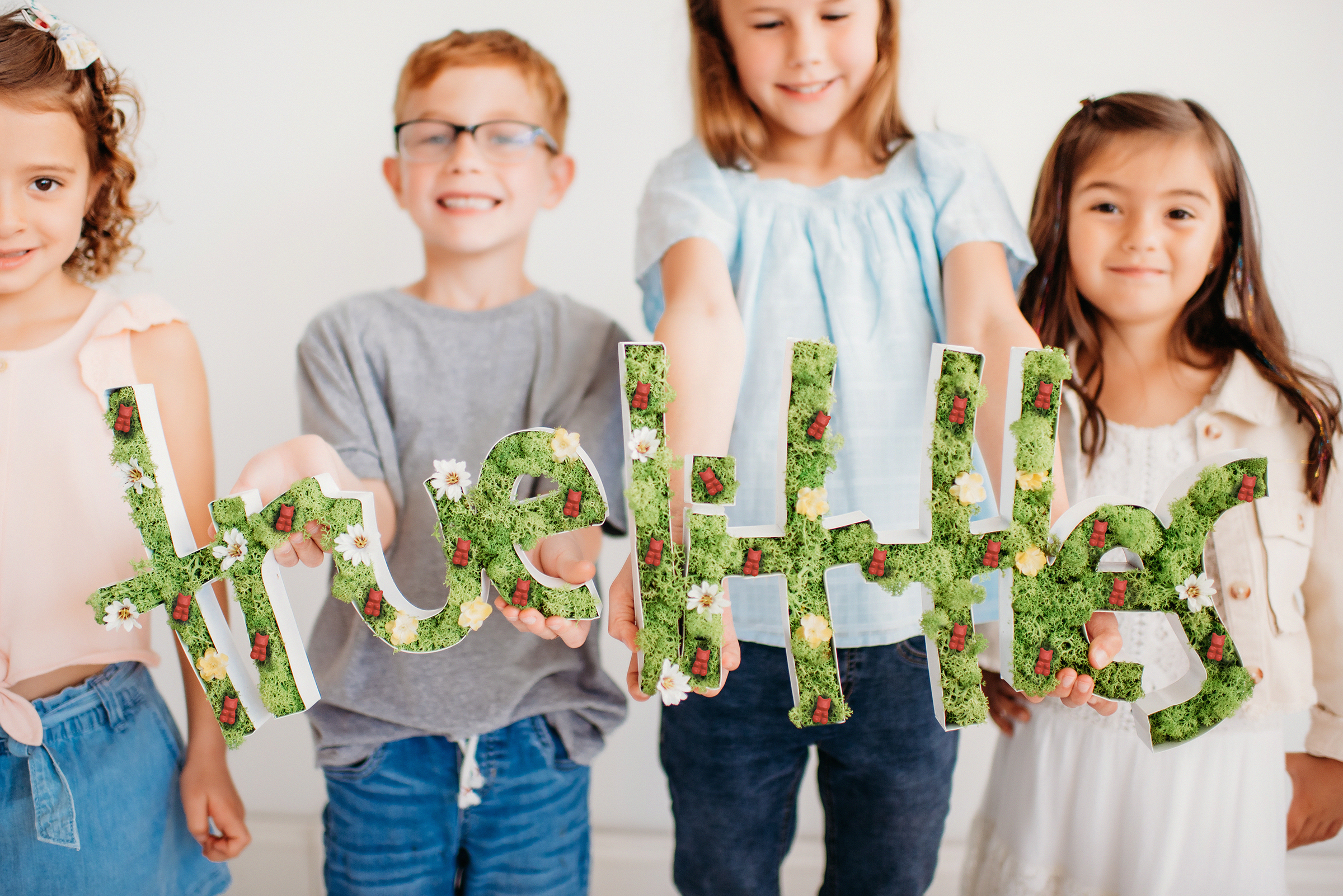 Four children spelling "True Littles"